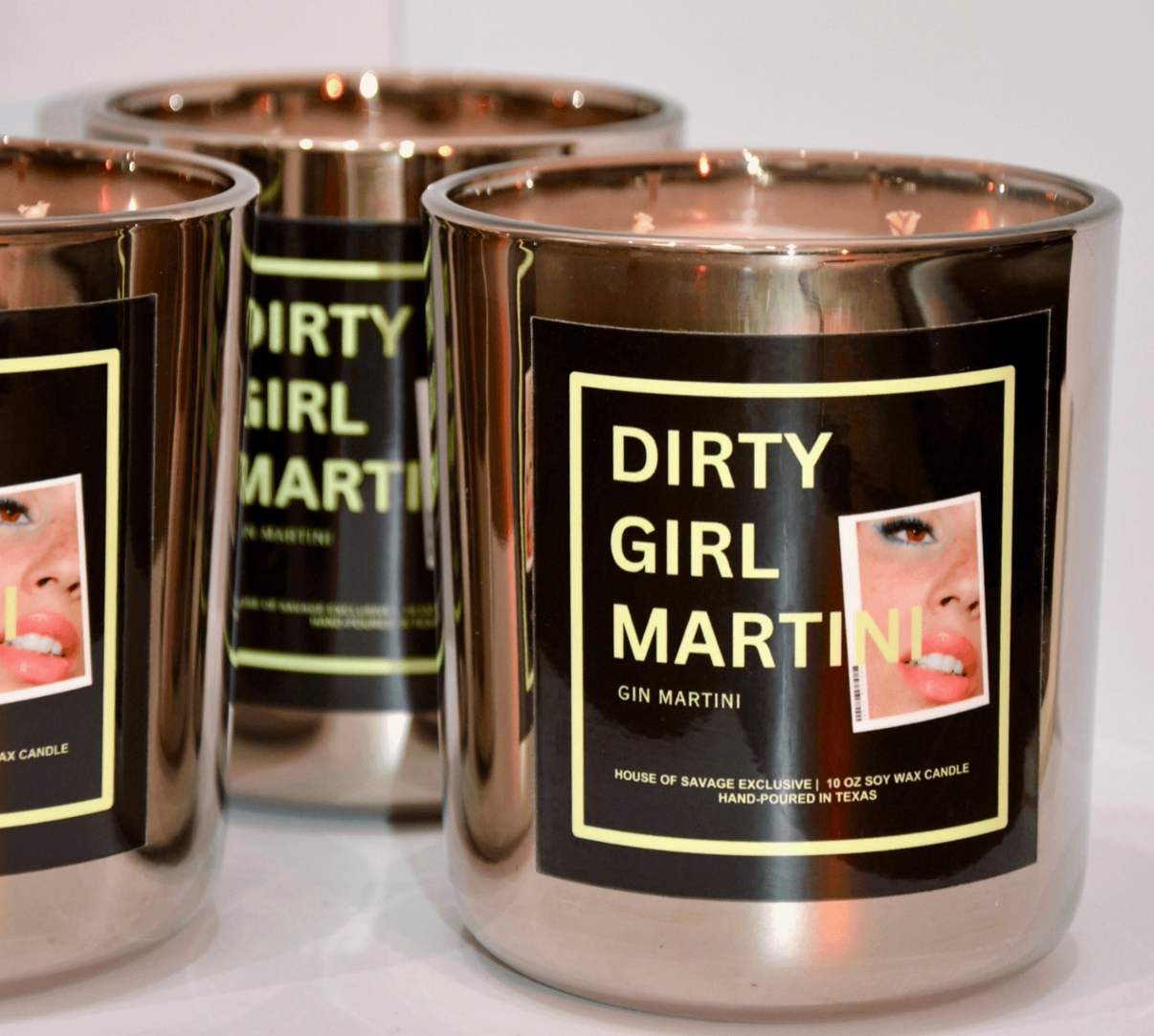Candle containers labeled 'Dirty Girl Martini' with a black label featuring a woman's face.