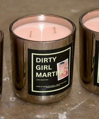 Candle with 'Dirty Girl Martini' label on a concrete surface
