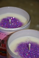 Two candles with purple glitter inside, one in a pink container.