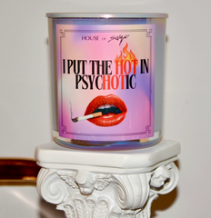 Candle with a colorful label featuring text and a mouth graphic on a decorative stand.