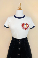 White t-shirt with a red heart design on a mannequin against a beige background