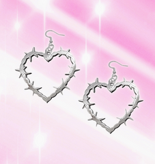 Barbed wire heart-shaped earrings on a pink and white gradient background