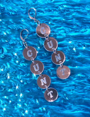 Silver earrings with 'C U N T' charms on a blue water background